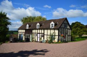 an old black and white house with a driveway at Whitewells Farm Cottages in Great Malvern