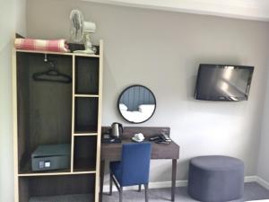 a room with a desk and a tv and a mirror at Garden Court Hotel in London +37 photos