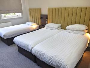 two beds in a hotel room with white sheets at Garden Court Hotel in London