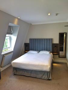 1 dormitorio con 1 cama grande y cabecero azul en Garden Court Hotel, en Londres