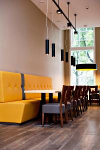 a dining room with a yellow couch and chairs at City Hotel Amsterdam in Amsterdam