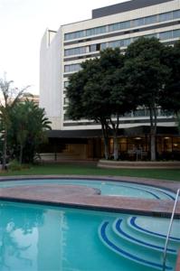 a swimming pool in front of a building at Southern Sun Pretoria in Pretoria