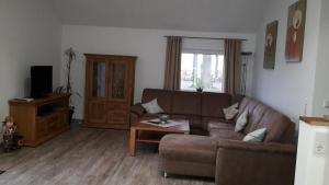 ein Wohnzimmer mit einem braunen Sofa und einem Tisch in der Unterkunft Ferienhaus Poppe in Löningen