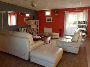 una sala de estar con muebles blancos y paredes rojas. en chambres des rosiers en Sennevières