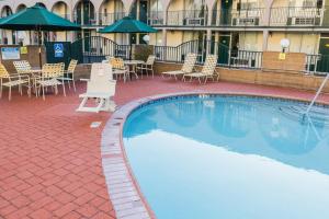 a large swimming pool with chairs and tables and umbrellas at Kings Inn Anaheim at The Park & Convention Center in Anaheim