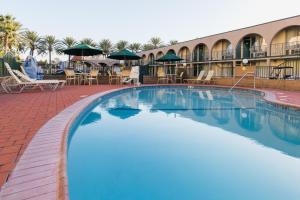 a large swimming pool with chairs and umbrellas at a hotel at Kings Inn Anaheim at The Park & Convention Center in Anaheim