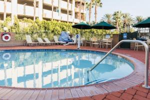 a swimming pool in a hotel with chairs and umbrellas at Kings Inn Anaheim at The Park & Convention Center in Anaheim