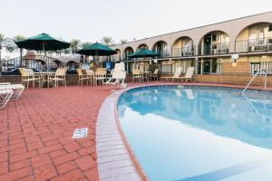 a swimming pool at a hotel with chairs and umbrellas at Kings Inn Anaheim at The Park & Convention Center in Anaheim