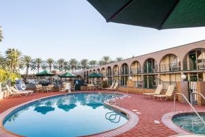 a large swimming pool in a resort with tables and chairs at Kings Inn Anaheim at The Park & Convention Center in Anaheim