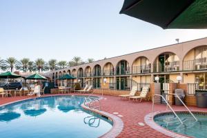 a large swimming pool in a hotel with tables and chairs at Kings Inn Anaheim at The Park & Convention Center in Anaheim