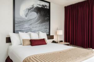 a large bed in a hotel room with a painting on the wall at Kings Inn Anaheim at The Park & Convention Center in Anaheim