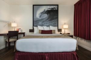 a large bed in a hotel room with a painting on the wall at Kings Inn Anaheim at The Park & Convention Center in Anaheim