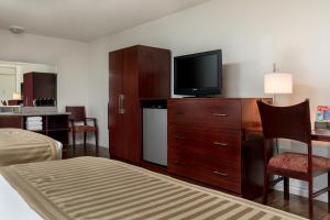 a hotel room with a television on a wooden dresser at Kings Inn Anaheim at The Park & Convention Center in Anaheim
