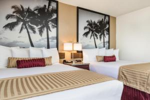 two beds in a hotel room with palm trees on the wall at Kings Inn Anaheim at The Park & Convention Center in Anaheim