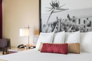 a bed with white pillows and a picture on the wall at Kings Inn Anaheim at The Park & Convention Center in Anaheim
