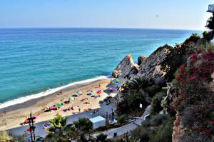 a beach with umbrellas and people on the beach at Casa Jazmin Carabeo in Nerja