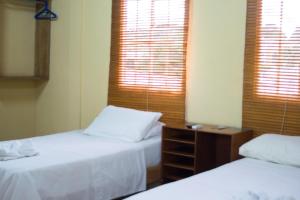 a bedroom with two beds and two windows with blinds at Hotel Valerie in Managua