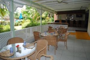 restauracja ze stołami i krzesłami na ganku w obiekcie Sunbay Hotel w mieście Christ Church