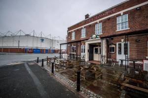 un edificio de ladrillo con mesas de madera fuera de él en The Rodney en Warrington