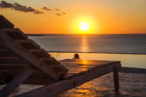 a person sitting on a dock watching the sunset at Kaladi Rock in Avlemonas