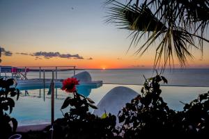 a sunset over the ocean with a swimming pool at Kaladi Rock in Avlemonas