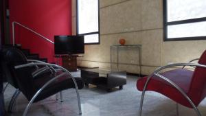 a living room with chairs and a tv and red walls at Platinum Hotel in Sao Paulo