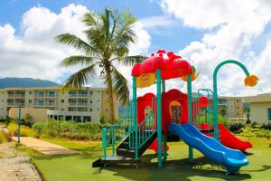 a playground in front of a building with a palm tree at LD Suites Punta Playa in Altagracia