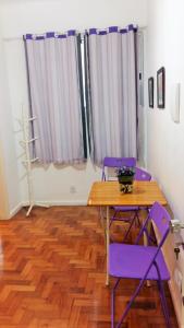 comedor con sillas moradas y mesa de madera en Apartamento Lausanne en Río de Janeiro