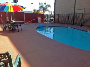 a swimming pool with a table and an umbrella at Studio 6 Suites Delano, CA in Delano