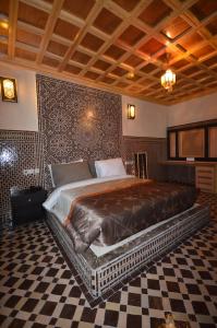 ein großes Bett in einem Zimmer mit einem karierten Boden in der Unterkunft Hôtel-Café-Restaurant Pyramides, in Taza