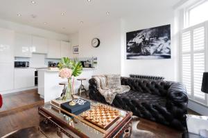 a living room with a black leather couch and a chessboard at Primrose Boutique Home in London
