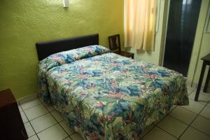 a bedroom with a bed with a floral comforter at Hotel Esperanza in Mazatlán