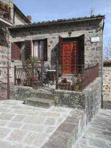 a stone house with a wooden door and a patio at Casa della piazza in Radicofani