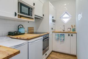 La cuisine est équipée de placards blancs et d'un four avec plaques de cuisson. dans l'établissement Beach House Apartment, à Cascais
