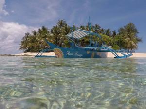 a blue boat in the water on a beach at Riad Masaya in General Luna