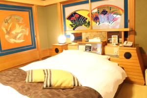 a bedroom with a bed and paintings on the wall at Munakata Pal (Love Hotel) in Munakata