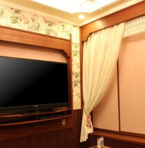 uma televisão de ecrã plano num quarto com uma cortina em Munakata Pal (Love Hotel) em Munakata