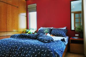 Chez Tram Homestay في هانوي: غرفة نوم بسرير وملاءات زرقاء وجدار احمر