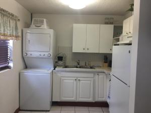 WhitbyにあるSagusta Gardens NCAのシンクと冷蔵庫を備えた白いキッチン