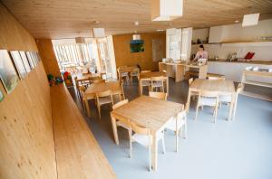 Habitación con mesas y sillas de madera y cocina. en Youth Hostel Punkl en Ravne na Koroškem