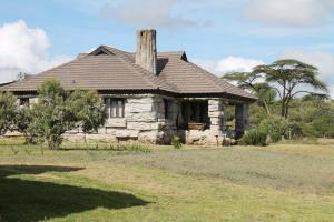 an old stone house with a roof on a field at Shwari Cottages in Naivasha