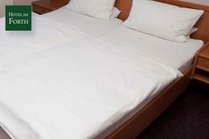 a pair of beds with white sheets and pillows at Hotel im Forth in Oyten
