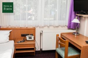 Zimmer mit einem Schreibtisch, einem Bett und einem Telefon. in der Unterkunft Hotel im Forth in Oyten