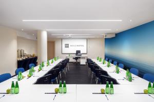 a conference room with long tables and chairs and a projector screen at Hotel Molo in Sopot