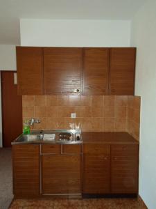 a kitchen with wooden cabinets and a sink at Apartments Branko in Nin