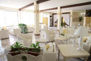 um átrio com cadeiras brancas, mesas e plantas em Hotel & Spa Villa del Mare - Adult Only em Maratea