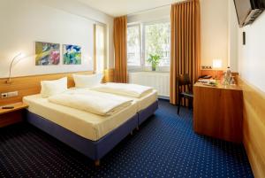 ケルンにあるMesseHotel Köln-Deutzのベッドとデスクが備わるホテルルームです。
