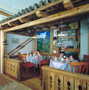 a dining room with tables and chairs and a painting at Hotel des Alpes in Molveno