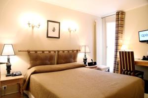 a bedroom with a bed and two lamps and a television at Hotel Albe Bastille in Paris