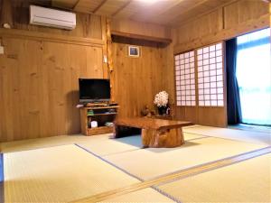 屋久島にあるCottage Yakusugi Houseのテーブルとテレビのあるリビングルーム
